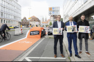 Bild Ein roter Fahrradweg-Teppich verläuft über ein falsch geparktes Auto auf einem Radweg an der Marienstraße. Die Kampagne "Verstell dich nicht – Respekt hat Effekt" haben am Donnerstag, 11. Juni 2026, der Leiter des Verkehrsplanungsamts, Frank Jülich, Mobilitätsbürgermeister Andreas Krieglstein und der Fraktionsvorsitzende der Grünen im Stadtrat, Alexander Kahl (v.l.n.r.) vorgestellt.