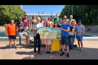 Bild Erste Reihe von links: Bürgermeister Andreas Krieglstein, Nathalie Griffin vom Clownprojekt e. V., Brauereiinhaberin Marlies Berneuther und Matthias Bach, Kaufmännischer Werkleiter von NürnbergBad, haben gemeinsam mit Teilnehmenden der Benefizaktion am Freitag, 10. Juli 2026, den Spendenscheck der Pyraser Landbrauerei an das Clownprojekt e. V. übergeben. Rund 200 Schwimmerinnen und Schwimmer hatten zuvor das Etappenziel von 30.000 Bahnen weit überschritten.
