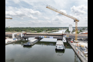 Bild Lückenschluss über dem Main-Donau-Kanal: Am Dienstag, 30. Juni 2026, hat das Projekt Hafenbrücken eine weitere Hürde genommen. Mithilfe zweier Spezialhebegeräte wurde ein 75 Meter langes und 520 Tonnen schweres Brückenteil aus Stahl auf zwei Lastschiffen zentimetergenau unter der Brückenlücke positioniert .