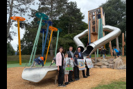 Bild Feierliche Eröffnung des neuen inklusiven Spielplatzes in der Grünanlage Ferdinand-Drexler-Weg (v.l.n.r.): Dr. Kerstin Schröder, Leiterin des Jugendamts, Oberbürgermeister Marcus König sowie Bürgermeister und Erster Sör-Werkleiter Christian Vogel am Montag, 28. Juli 2025, mit zahlreichen Kindern. Dank einer umfangreichen Kinderbeteiligung wurde der Spielplatz mit den Kindern entwickelt und für die Kinder gebaut . Die Kinder halten Abdrucke der selbstgebauten Modelle ihrer Wunschspielgeräte aus den Beteiligungen in der Hand. Sör hat viele Wünsche umgesetzt.