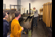 Bild Ein Sör-Mitarbeiter taucht eine fertige Holzlatte in ein Bad mit Imprägnierungsmittel. Das Holz ist nun gegen Feuchtigkeit geschützt. 