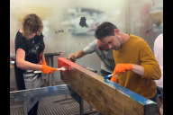 Bild Nach der fachkundigen Überarbeitung in der Sör-Schreinerwerkstatt wird die alte Parkbank von Mitarbeitenden der noris inklusion farbenfroh bemalt.