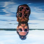 Mann mit Sonnenbrille steckt Kopf aus dem See