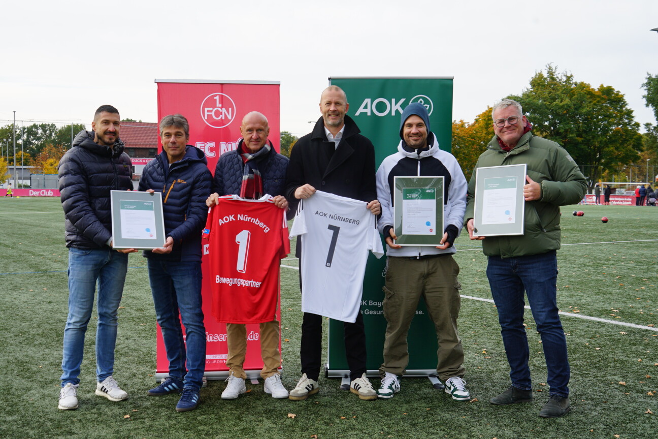 Menschen bei der Übergabe von Förderurkunden an Schulen.