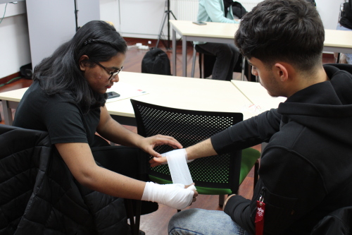 Zwei Schülerinnen legen probeweise Verbände beieinander an