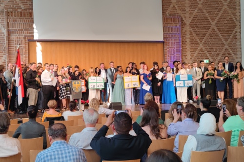 Foto von der IBOS Abschlussfeier. Alle Schülerinnen und Schüler auf der Bühne mit den Schulleitungen, IBOS Mitarbeiterinnen sowie Politiker innen.