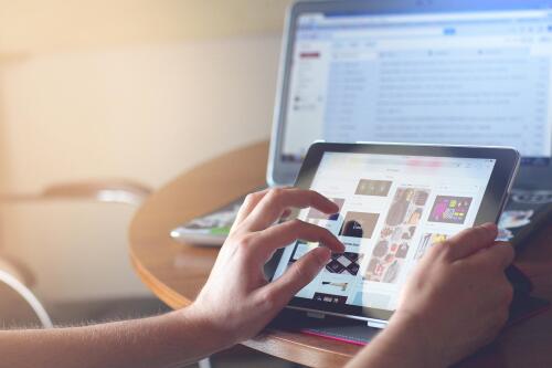 Person, von welcher nur die Arme und Hände zu sehen sind, bei der Internetrecherche auf einem Tablet