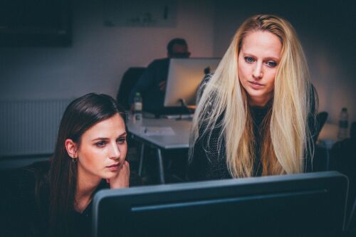 zwei Frauen, die konzentriert auf einen Monitor schauen