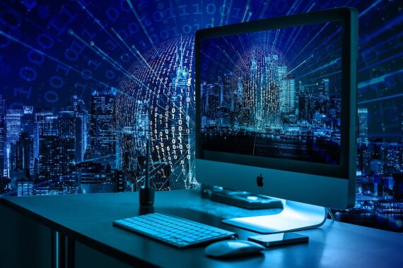 Arbeitsplatz mit Monitor, Tastatur und Maus umgeben von einem blauen Hintergrund mit den Zahlen 0 und 1