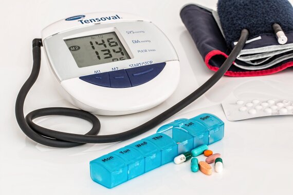 Blutdruckmessgerät, verschiedenfarbige Tabletten und Tablettenwochenbox