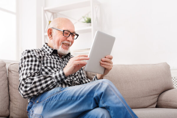 Älterer Herr liest Neuigkeiten auf dem Tablet