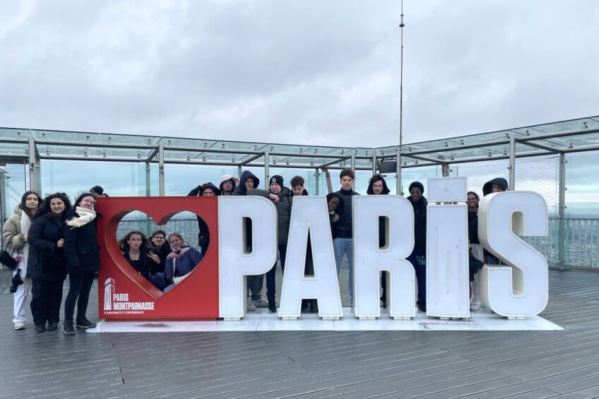 Eine Schülergruppe vor einem Schild mit der Aufschrift Paris, Bild © A. Lorenz / Sigena-Gymnasium
