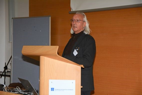 Prof. Dr. Elmar Rieger steht am Pult und hält Vortrag über Zusammenhang von Armut und Reichtum - Ursachen und Strukturen