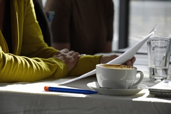 Ein Mensch liest bei einer Tasse Kaffee vor.