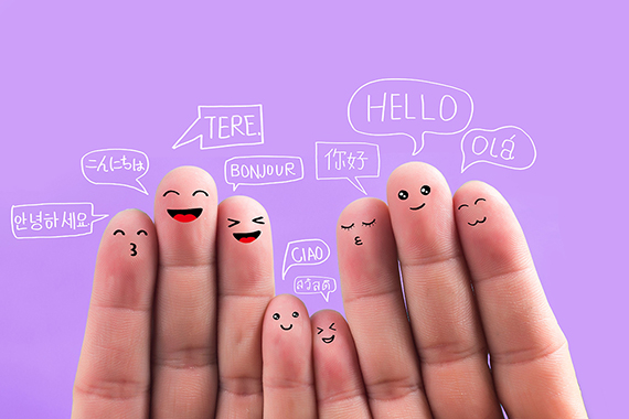 Bemalte Fingerspitzen und Sprachblasen in verschiedenen Sprachen