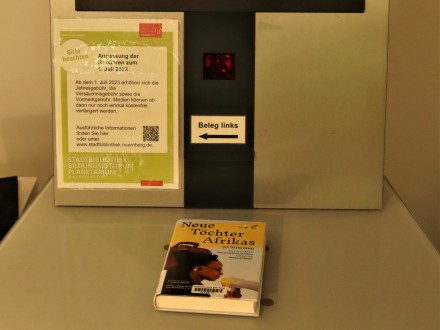 Das Bild zeigt die Ablage·fläche vom Ausleih·automaten. In der Mitte von der Ablage·fläche ist ein markierter Bereich. Auf dem markierten Bereich liegt ein Buch.