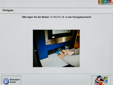 Das Bild zeigt den Rückgabe·automaten. Eine Person schiebt ein Buch in das Rückgabe·fach.