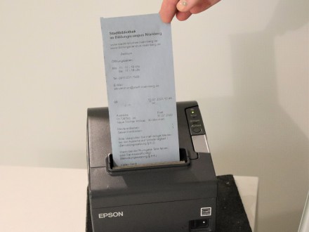 Das Bild zeigt: Aus einem kleinen Drucker kommt der Ausleih·beleg.
