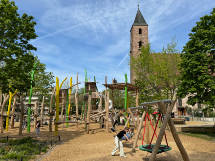 Foto von einem neuen Spiel·platz in Gibitzenhof. Im Hintergrund sieht man den Turm von einer Kirche.