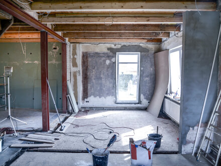 Foto von einem Raum in einem Gebäude. Der Raum ist eine Bau·stelle und wird gerade saniert. In dem Raum sind Werkzeuge und Eimer.