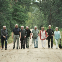 Acht Personen laufen einen Waldweg entlang in Richt ung Kamera.