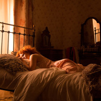 Filmstill aus "Das Glück der Welt": Eine Frau liegt auf einem Bett und schläft.
