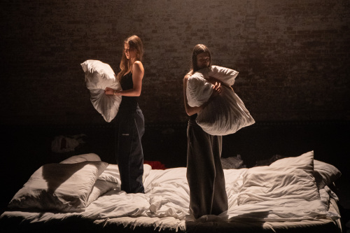 Zwei Schauspielerinnen des Jugendclubs des Oldenburgischen Staatstheaters stehen auf einem Bett und halten Kissen.