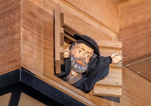 Foto: Eine geschnitzte Hans-Sachs Figur schaut im Bodenbereich der Laurentiusorgel in der Lorenzkirche aus einer Klappe heraus. © Thomas Bachmann, BambergVerwendung laut Abbildungsvertrag