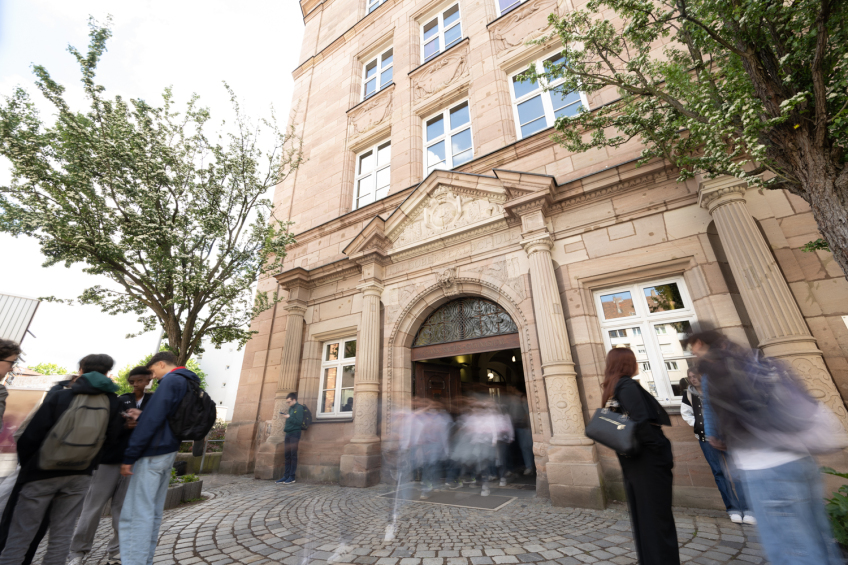 Foto: Eingangstür und Vorplatz des Hans-Sachs Gymnasiums mit Schülern., Bild © Christine Dierenbach/ Stadt Nürnberg / Stadt Nürnberg/Christine Dierenbach