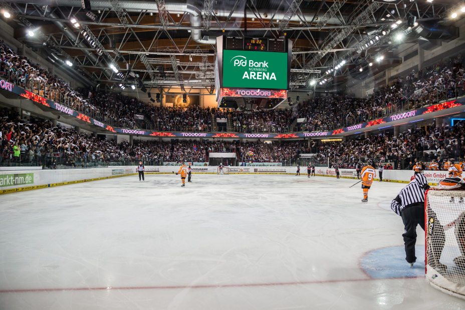 Foto: Eishockeyhalle mit voll besetzten Zuschauerrängen und Spielern auf dem Eis. Große Anzeigentafel mit dem Schriftzug psd Bank Nürnberg Arena., Bild © www.metal-fotos.de