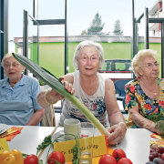 Seniorinnen sitzen gemeinsam am Tisch, auf dem Gemüse liegt