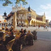 Die Innenstadt Krakaus, im Vordergrund sitzen Menschen in einem Straßencafé.