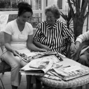 Eine junge Altenpflegerin liest gemeinsam mit einer Seniorin in einer Zeitschrift.
