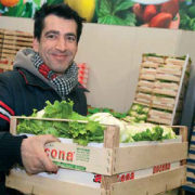 Ein Verkäufer auf dem Großmarkt hält einen Karton mit Salatköpfen