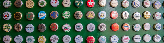 Kronkorken verschiedener Biermarken an einer Wand