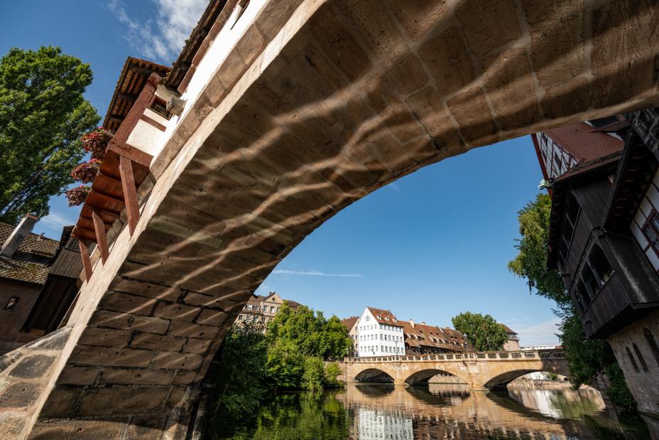 Foto: Wasserspiegelungen im Bogen der Henkerbrücke. Im Hintergrund ist die Maxbrücke zu sehen.