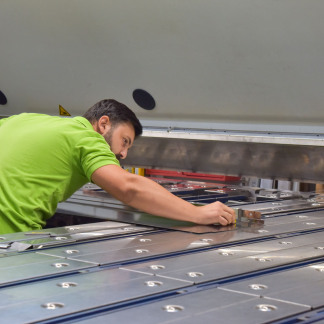 Nachdem es von einem Laser-Cutter geschnitten und gestanzt wurde, biegt ein Mitarbeiter das Metall an einer Maschine um.