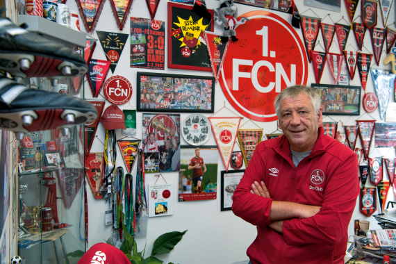 Fanbeauftragter des 1.FCN Jürgen Bergmann vor einer Wand mit vielen Wimpeln