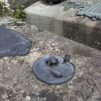 Das mit Blütenknospen geschmückte Seerosenblatt, auf dem ein Frosch sitzt, schuf der Epitaphienkünstler Thomas Haydn, der die Tradition des kunstvollen Bronzegusses fortführt.