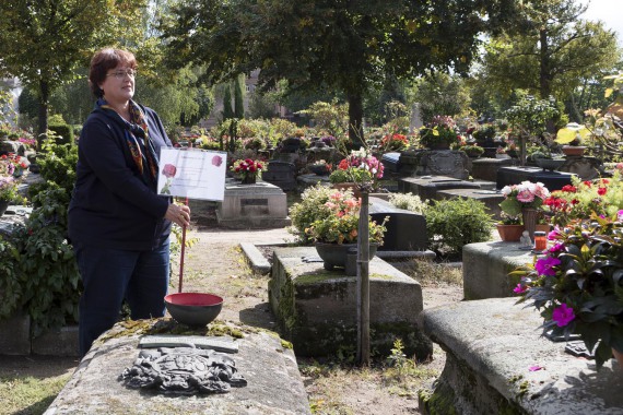Eine Grabpflegerin markiert mit einem Hinweisschild ein freies Grab.