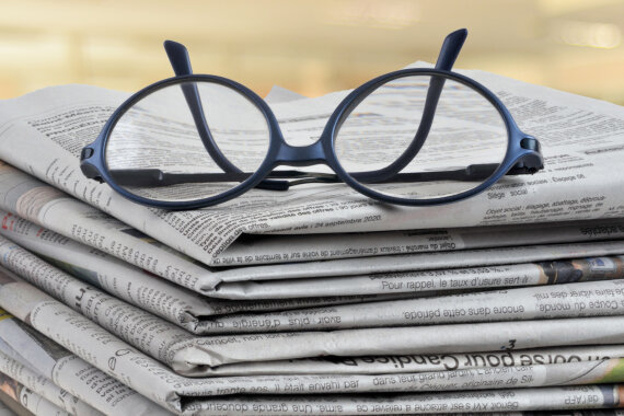 Brille liegt auf Stapel mit Zeitungen, Eyeglasses lying on a pile of newspapers close up