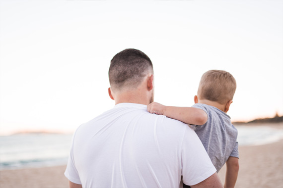 Vater mit Sohn auf dem Arm am Strand