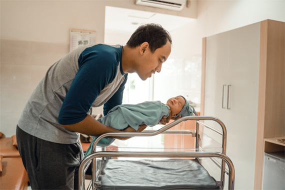 Mann im Krankenhaus mit Neugeborenem