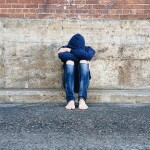 Jugendlicher sitzt an Mauer