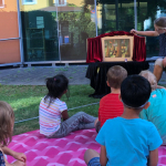 Kinder im Garten vor Puppentheater