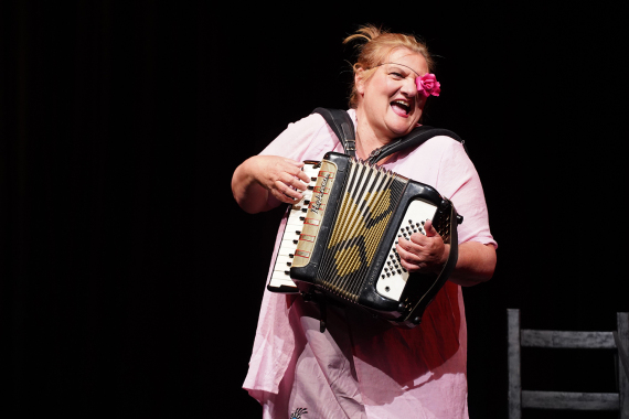 Frau in rosa spielt Ziehharmonika