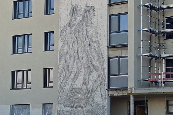 Zwei Figuren auf der Betonfassade einer Gebäude, ein Werk von Gerhard Mayer