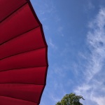 Ein roter Sonnenschirm vor einem blauen Himmel