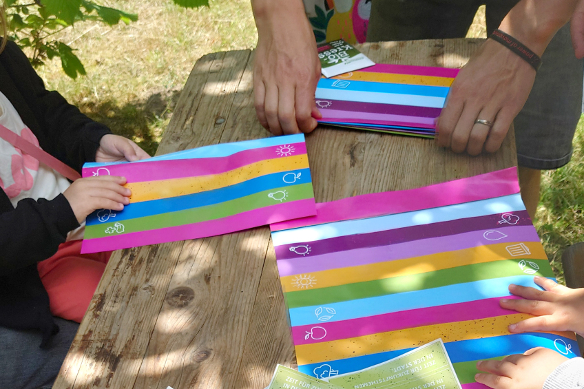 Arbeitstisch, an dem bunte Papierfächer gefaltet werden