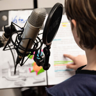 Junge steht vor Mikrofon 